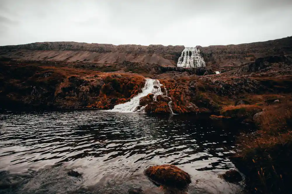 A lower fall dropping into a dark pool between red-brown rocks