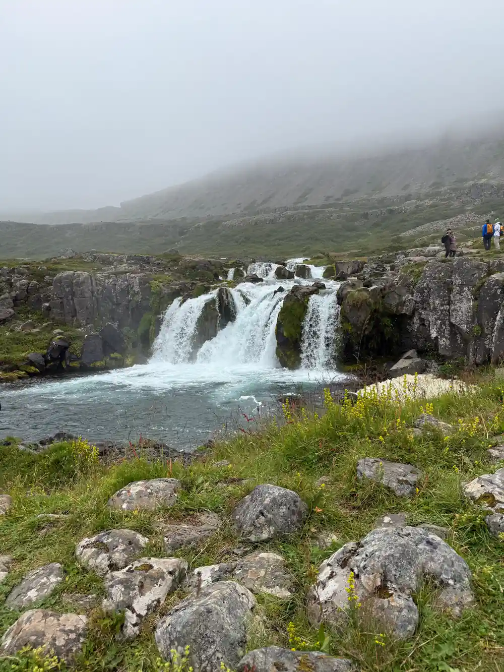 A lower fall in mist with people on the path above it
