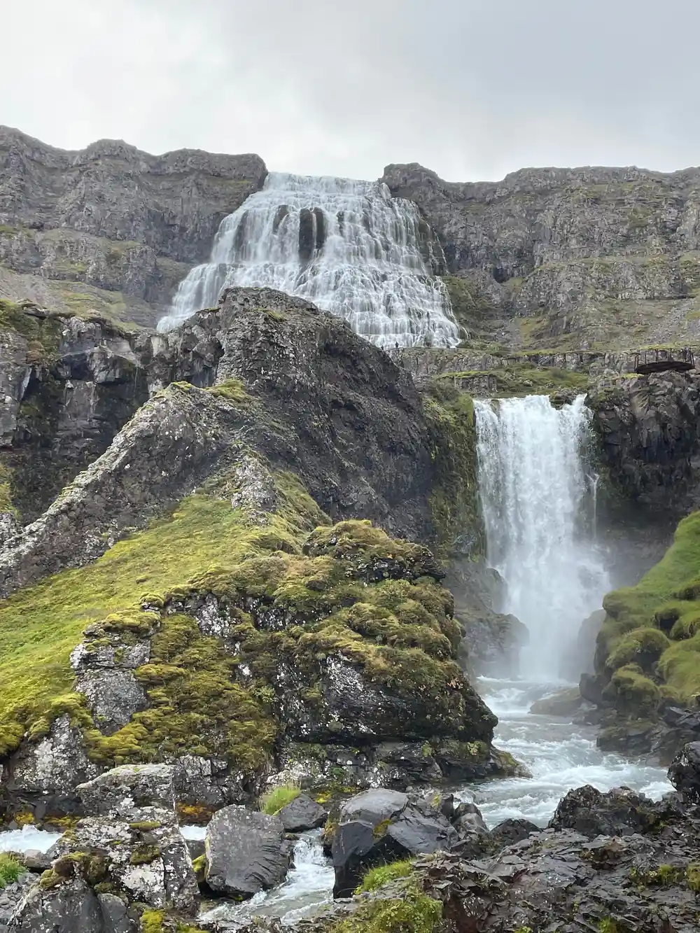 A narrow fall between mossy crags with Dynjandi behind it