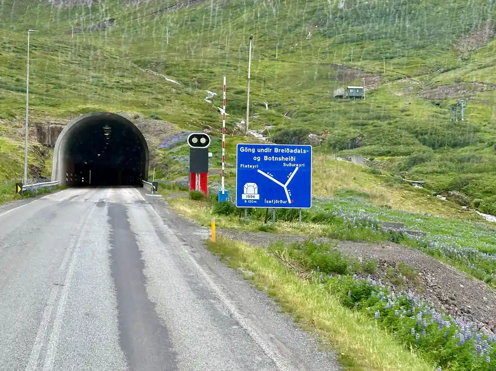 The road running into a tunnel mouth under a green mountain