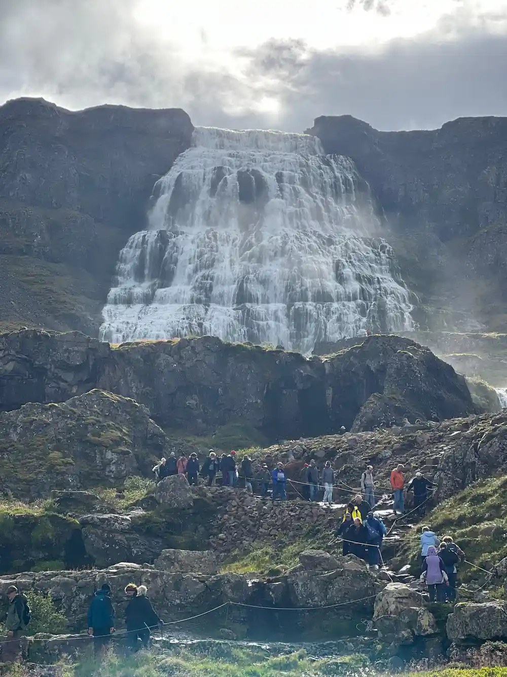 Visitors climbing the path in a line below the full width of Dynjandi