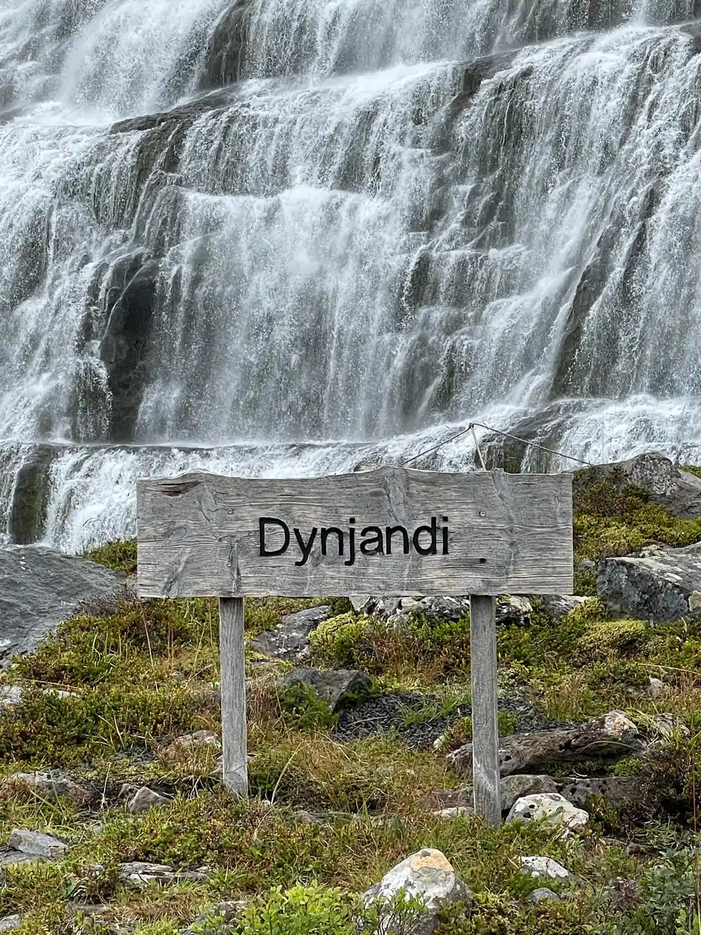 The weathered wooden Dynjandi sign in front of the falls