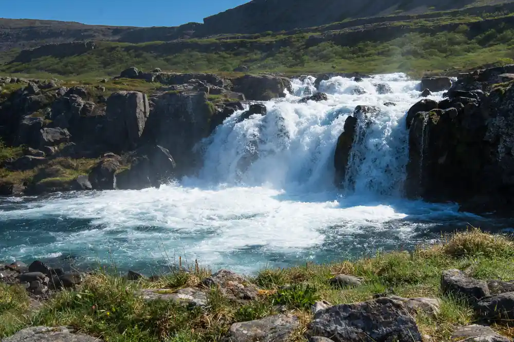 A wide lower fall churning into a turquoise pool